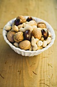 Walnuts, chestnuts and peanuts in white bowl