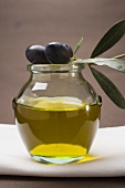 Schwarze Oliven am Zweig auf Glas Olivenöl