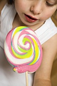 Child holding pastel-coloured lollipop