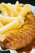 Currywurst (sausage with ketchup & curry powder) & chips (close-up)