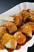 Sausage with ketchup and curry powder in paper dish