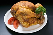 Spicy roast chicken, garnished with parsley and tomato