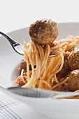 Spaghetti with meatballs and tomato sauce on fork