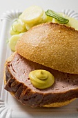 Leberkäse in roll with mustard & potato salad on paper plate