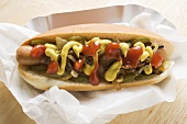 Hot dog with mustard, ketchup, gherkins and onions