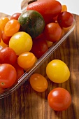 Various types of tomatoes in plastic tray on chopping board