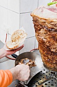 Making a döner kebab: filling pita bread with meat