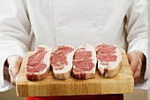 Chef holding sirloin steaks on chopping board