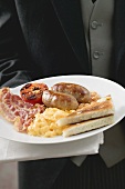 Butler serving English breakfast on plate