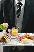 Butler serving English breakfast on tray