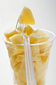 Pineapple chunks in a plastic beaker with a plastic fork