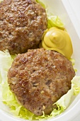 Burgers with mustard and lettuce garnish