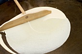 Making crêpes (spreading mixture on hotplate)