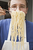 Koch hält Spaghettiheber mit gekochten Spaghetti
