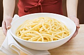 Woman holding bowl of cooked macaroni