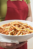 Woman holding bowl of macaroni with mince sauce