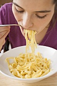 Young woman eating ribbon pasta