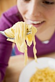 Young woman eating ribbon pasta