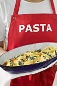 Woman in apron serving baked pasta dish