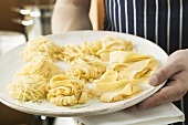 Person holding plate of home-made pasta