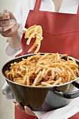 Woman eating macaroni with mince sauce out of pan