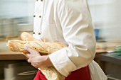 Chef hurrying through kitchen with baguettes