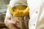 Koch läuft mit Spaghetti im Kochtopf durch Küche