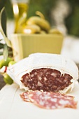 Salami and green olives on table out of doors