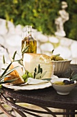 Cheese, olives and olive oil on table out of doors
