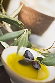 Olive oil in small bowl with black olives