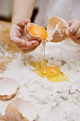 Making pasta dough: a child breaking an egg