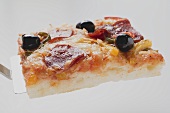 Slice of pepperoni pizza with peppers and olives