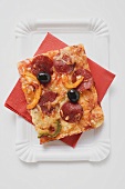 Stück Pizza mit Peperoniwurst, Paprika und Oliven
