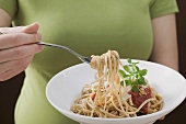 Woman eating linguine with tomato sauce