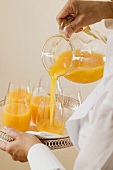 Chambermaid pouring orange juice into glass