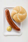 Sausage (bratwurst) with mustard & bread roll on paper plate