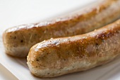 Two sausages (bratwursts) on paper plate (close-up)
