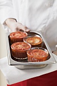 Chef holding dish with four small tomato gratins