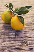 Two oranges with leaves on wooden background