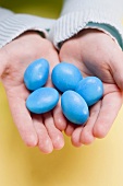 Child's hands holding blue sugar eggs