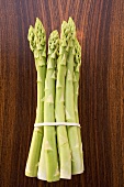 A bundle of green asparagus on wooden background