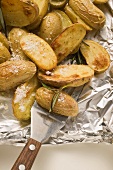 Rosemary potatoes on aluminium foil with spatula