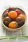 Different types of tomatoes in wooden dish