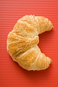 Croissant on red background (overhead view)