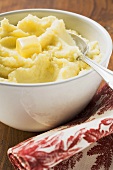 Kartoffelpüree mit Butter in weisser Schüssel mit Löffel