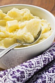 Mashed potato with butter in white bowl with spoon