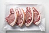 Four raw pork chops on paper