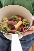 Person holding strainer containing coloured pasta
