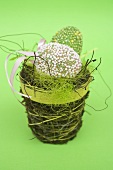 Two green decorated eggs in Easter nest