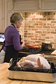 Woman at stove cooking accompaniments for Thanksgiving meal (USA)